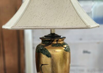 Gold vase lamp with white lampshade.