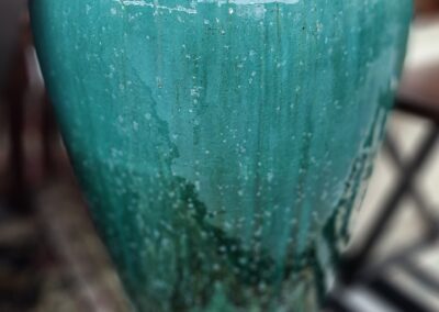 Large turquoise ceramic vase on carpet.
