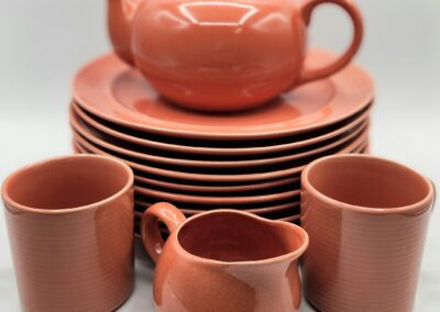 Orange ceramic tea set with plates and cups.