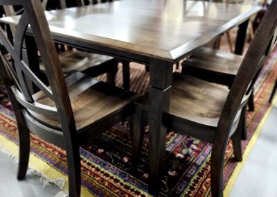 Wooden dining table set on colorful rug.