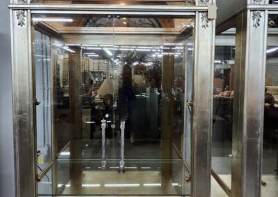 Ornate, arched silver display cabinet with glass doors.