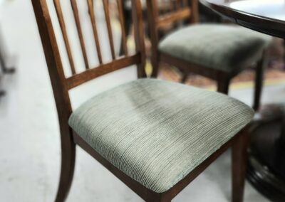 Wooden chair with green cushioned seat.