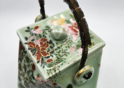 Floral square teapot with ornate handle.