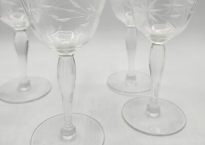 Four etched glass goblets on white background.