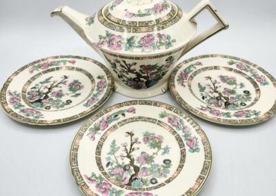 Floral teapot set with three matching plates.
