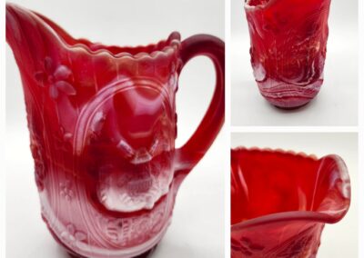 Red glass pitcher with embossed floral patterns.