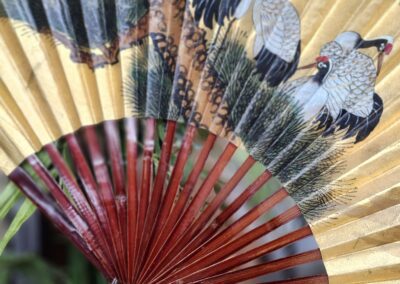 Decorative fan with painted cranes design.