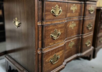 Wooden dresser with ornate brass handles.