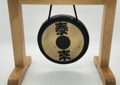 Small gong on wooden stand with symbols.