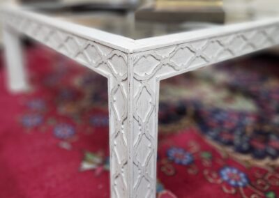White carved table on red patterned rug.