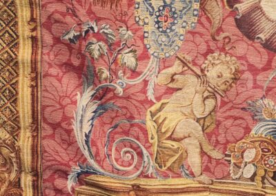 Tapestry featuring cherub playing flute, ornate design.