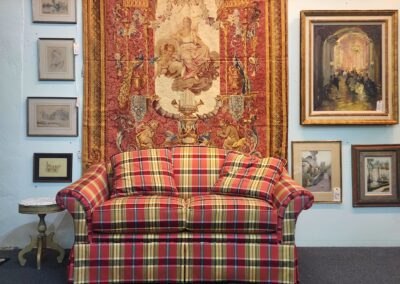 Plaid sofa, tapestry, and framed art display.
