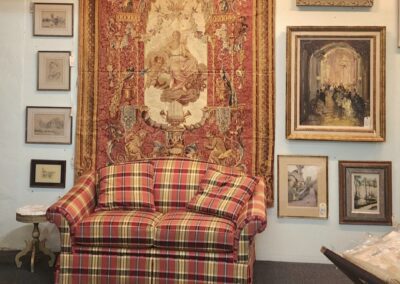 Plaid sofa and ornate tapestry in gallery.