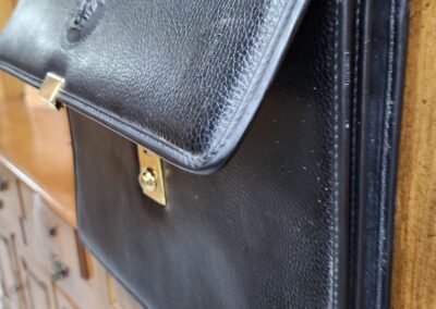 Black leather briefcase on wooden dresser.