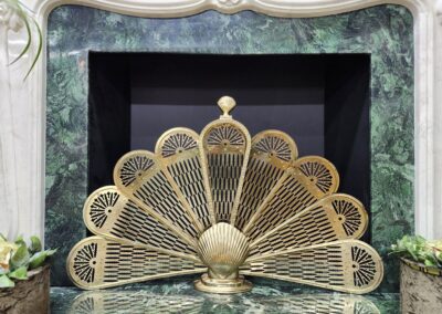 Golden peacock decor in ornate fireplace setting.