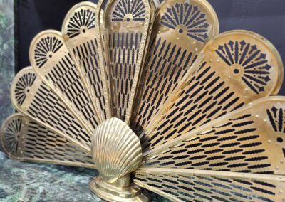 Ornate brass fan-shaped fireplace screen display.