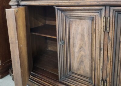 Wooden cabinet with open door and drawer.