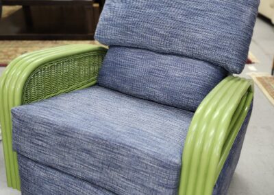 Blue cushioned chair with green wicker arms.