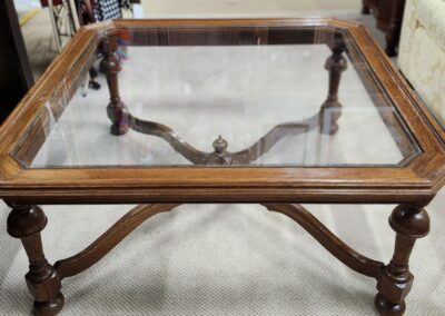 Wooden glass-top table with ornate legs.