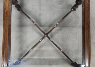 Wooden glass-top table with metal crossbars.