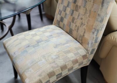 Checkered upholstered chair beside glass table.
