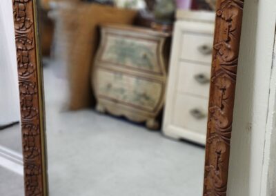 Ornate wooden mirror reflecting room interior.