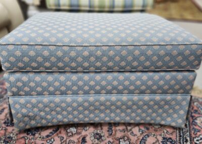Blue patterned ottoman on a patterned rug.