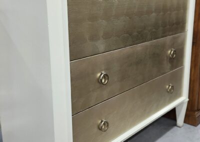 White dresser with textured gold drawers.