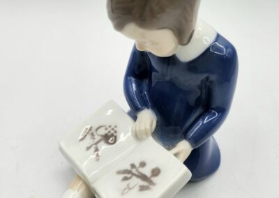 Porcelain figurine of girl reading a book.