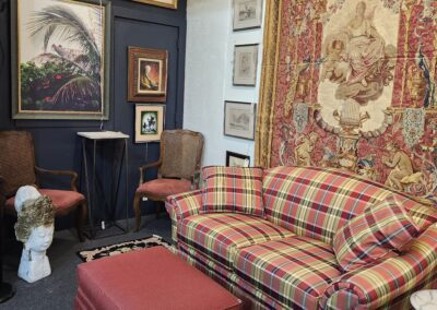 Plaid sofa, tapestry, and artwork in room.