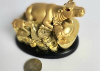 Golden cow figurine on coins, white background.