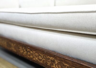 Ornate wooden sofa with white cushions.