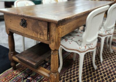 Wooden table with white chairs, patterned carpet.