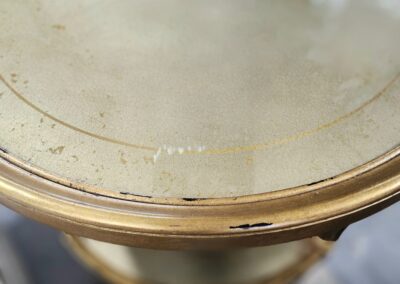 Round gold table with distressed surface.