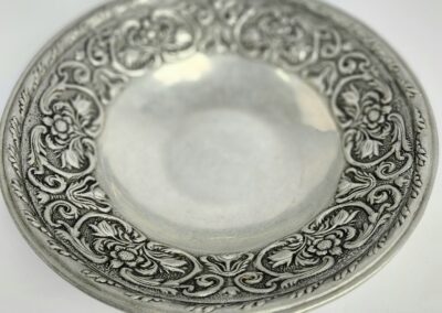 Ornate silver plate with intricate floral design.