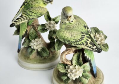 Porcelain parakeet figurines with floral base.