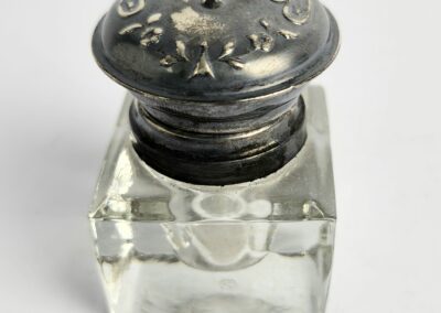 Ornate silver-topped glass inkwell on display.