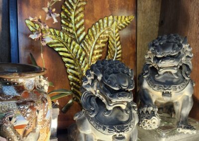 Decorative statues and vase on wooden shelf.