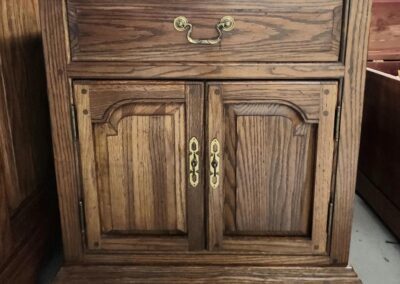 Wooden cabinet with brass handles and drawer.