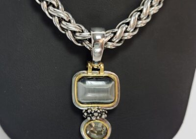 Silver necklace with two-tone pendant displayed.