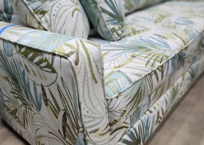 Floral-patterned sofa with green and blue leaves.