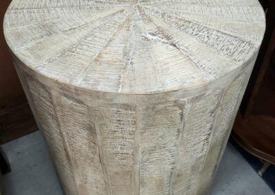 Wooden cylindrical table with textured surface.