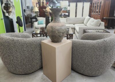 Gray chairs with vase on pedestal display.