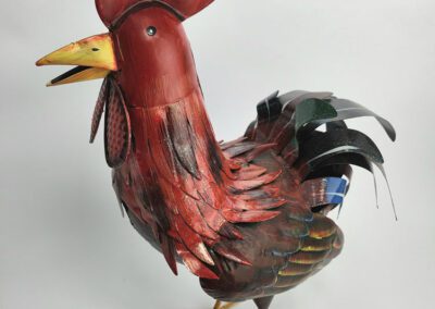 Red metal rooster sculpture on white background.