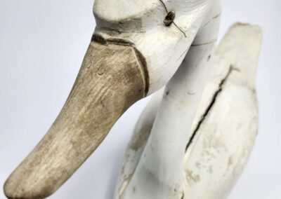 Weathered wooden duck decoy with cracks.