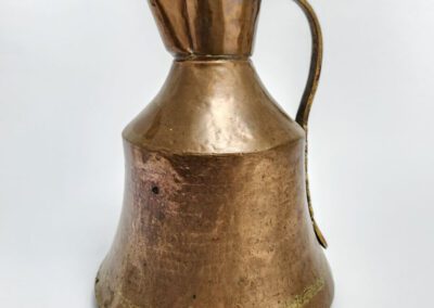 Copper jug with a handle on white.