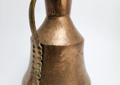 Antique copper jug with decorative handle.