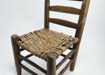 Wooden chair with woven seat, white background.