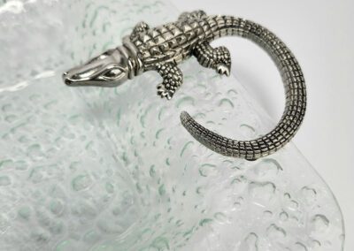 Metal alligator figure on textured glass surface.