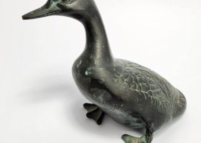Bronze duck sculpture on white background.